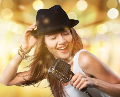Young woman wearing hat singing into microphone